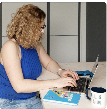 Blond lady in blue top working on a laptop